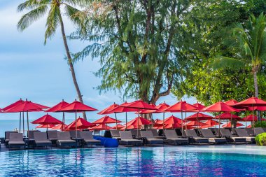 Sıcak açık yüzme havuzu etrafında güzel şemsiye ve sandalye