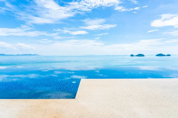 Beautiful outdoor swimming pool with sea ocean on white cloud bl — Stock Photo, Image