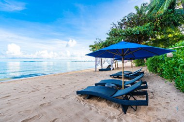 Tropikal plajda güzel şemsiye ve boş yatak sandalyesi ve