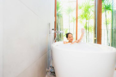 Portre genç güzel Asya kadın almak bir banyo içinde bathtub
