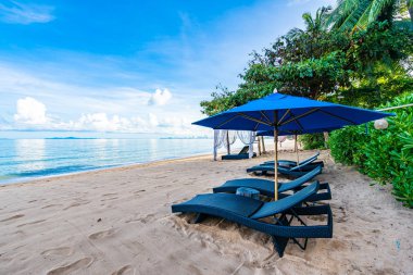 Tropikal plajda güzel şemsiye ve boş yatak sandalyesi ve