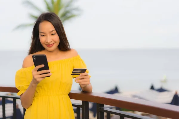 Schöne asiatische Frauen zeigen Kreditkarte mit Meerblick — Stockfoto