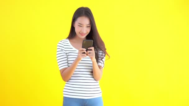 黄色のスマートフォンを使った美しいアジア系女性の映像 — ストック動画