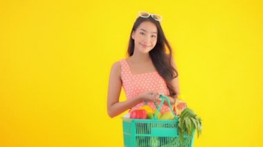 Güzel Asyalı kadının elinde sepet dolusu sebze ve meyve tutarken çekilmiş görüntüler.