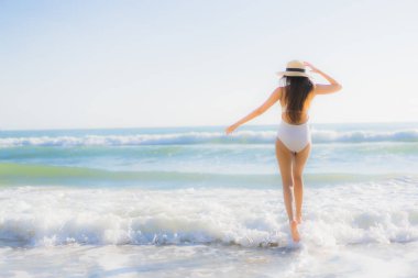 Güzel bir Asyalı kadın portresi. Okyanus sahillerinde mutlu bir gülümseme ve tatil için mavi bir gökyüzü.