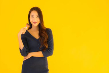 Sarı izole arkaplanda makyaj fırçası olan güzel bir Asyalı kadın portresi.