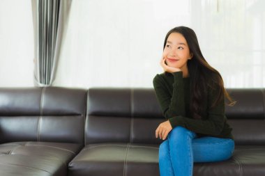 Güzel bir portre. Genç Asyalı kadın. Oturma odasındaki kanepede rahatla.