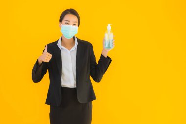 Güzel bir iş kadını portresi. Maske takıyor. Korunmak için alkol jeli kullanıyor.