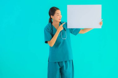 Fotokopi için boş kâğıt tahtası olan güzel Asyalı genç doktor kadın hastane ve klinikteki sağlık hizmetleri konseptinde mavi izole edilmiş arka plan.