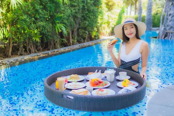 ポートレート美しい若いアジアの女性幸せな笑顔で浮遊朝食でトレイ上のスイミングプール — ストック写真
