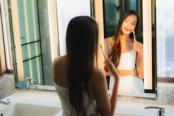 肖像画美しい若いアジアの女性バスルームのインテリアで歯を磨く — ストック写真