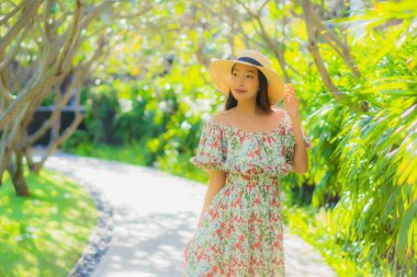 Güzel bir Asyalı kadın portresi. Mutlulukla yürüyor, bahçe manzarasının tadını çıkarıyor.