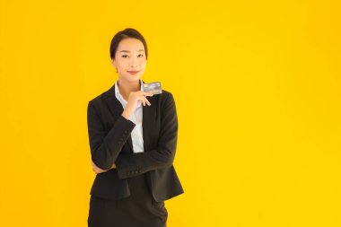 Sarı izole edilmiş arka planda kredi kartı olan güzel, genç Asyalı kadın portresi.