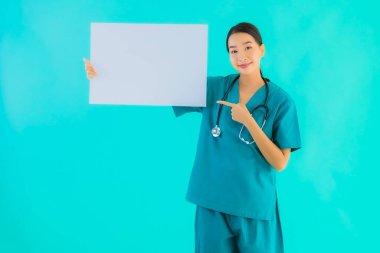 Fotokopi için boş kâğıt tahtası olan güzel Asyalı genç doktor kadın hastane ve klinikteki sağlık hizmetleri konseptinde mavi izole edilmiş arka plan.