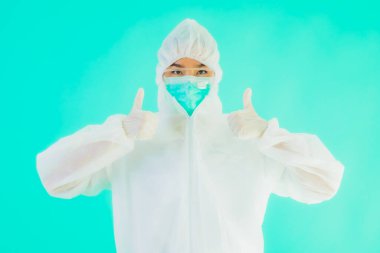 Güzel, genç Asyalı doktor kadın portre. Koronavirüsten ya da mavi arka planda kovid19 'dan korunmak için ppe ya da kişisel koruyucu ekipman takıyor.