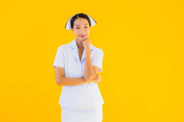 Güzel Asyalı genç Taylandlı hemşirenin portresi klinikteki ve hastanedeki hastalar için sarı izole edilmiş arka planda birçok eylem çalışmasında yer alıyor.