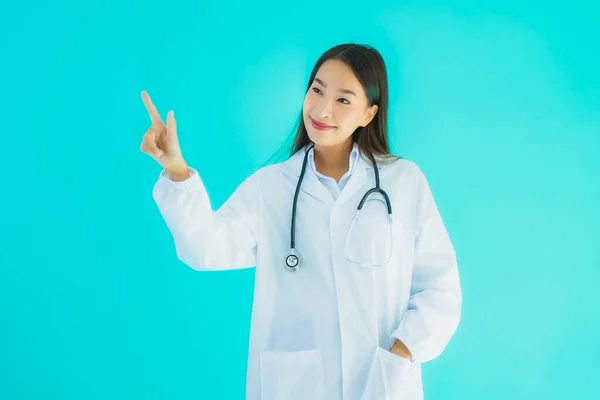 ポートレート美しいです若いですアジアの医師女性とともにStethoscope用のクリニックや病院での使用上の青隔離された背景 — ストック写真