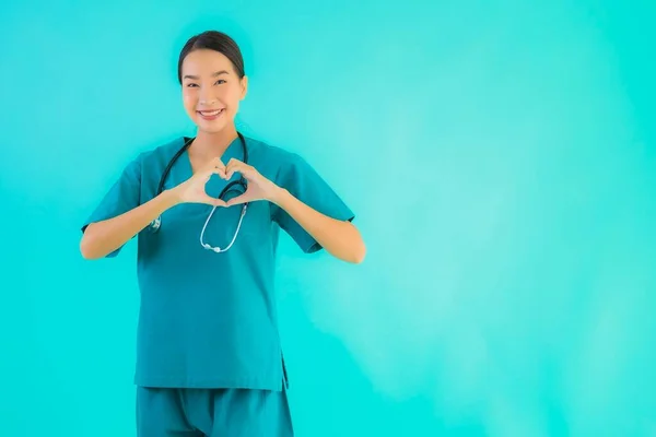 Portrait beautiful young asian doctor woman happy smile show heart shape for work in hospital and clinic on blue isolated background