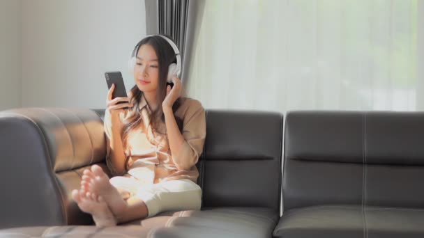 Metraje Hermosa Mujer Asiática Escuchando Música Con Auriculares Teléfono Inteligente — Vídeos de Stock