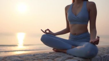 Kadının sağlık için gün doğumunda plajda meditasyon yaptığı görüntüler.