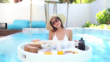 Güzel Asyalı bir kadının, tatil için otel tatil beldesinde yüzme havuzunda dinlendiği görüntüler.