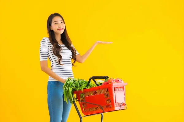 ポートレート美しい若いアジアの女性スーパーマーケットから食料品を買い物し 黄色の隔離された背景にカート — ストック写真
