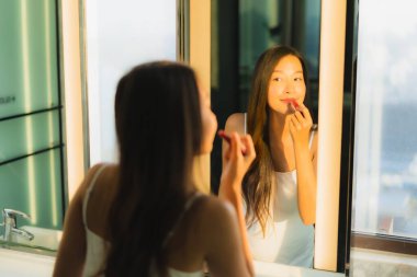 Güzel bir Asyalı kadın portresi makyaj malzemesi makyaj malzemesi ve yüz makyajı ile banyo içinde yüz maskesi.