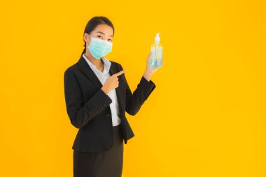 Güzel bir iş kadını portresi. Maske takıyor. Korunmak için alkol jeli kullanıyor.