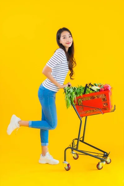 来自超级市场和黄色独立背景购物车的漂亮年轻亚洲女人的画像 — 图库照片