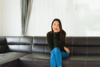 Güzel bir portre. Genç Asyalı kadın. Oturma odasındaki kanepede rahatla.