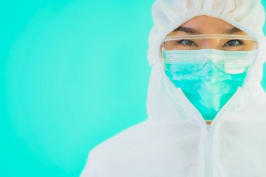 Güzel, genç Asyalı doktor kadın portre. Koronavirüsten ya da mavi arka planda kovid19 'dan korunmak için ppe ya da kişisel koruyucu ekipman takıyor.