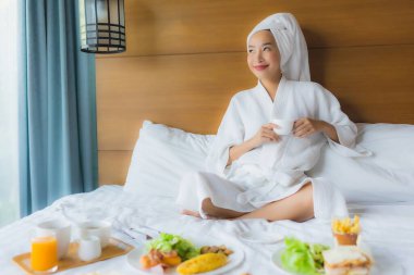 Genç Asyalı bir kadının portresi. Yatak odasında kahvaltı. İç tarafta.