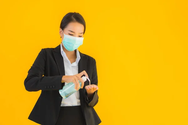 肖像画美しい若いビジネスアジアの女性は 黄色の隔離された背景にCoid19やコロナウイルスから保護するためにアルコールジェルを使用マスクを着用 — ストック写真