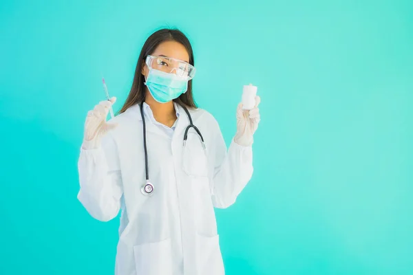 Portrait beautiful young asian doctor woman with vaccine syringe and drung or medicine bottle for use in hospital or clinic on blue isolated background