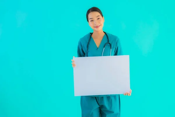 Portrait beautiful young asian doctor woman with empty paper board for copy space on blue isolated background - Healthcare in hospital and clinic concept