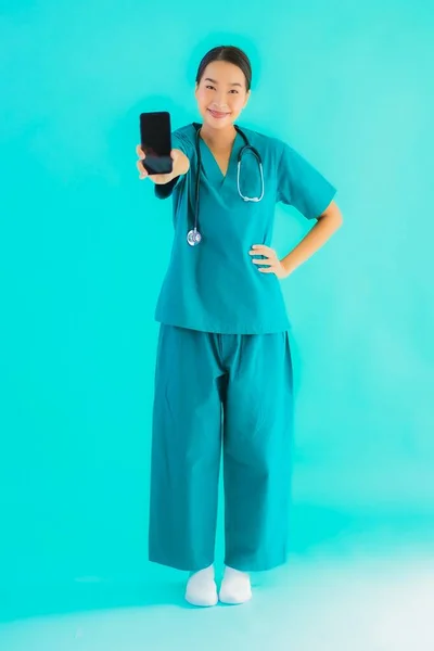 肖像画美しい若いアジアの医師の女性ショースマートフォン上の青隔離された背景 — ストック写真