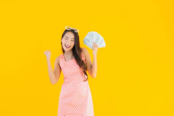 肖像美しい若いアジアの女性ショー多くの現金とお金上の黄色隔離された背景 — ストック写真