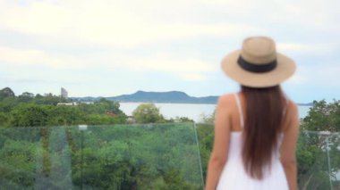 Sahilde hasır şapkalı güzel Asyalı bir kadının görüntüleri.