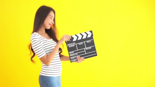 黄色に隔離された映画のクラッパーを持つ美しい若いアジアの女性のクローズアップ映像 — ストック動画