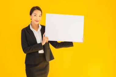 Güzel bir portre. Genç Asyalı kadın, sarı izole edilmiş arka planda boş beyaz tahta gösteriyor.
