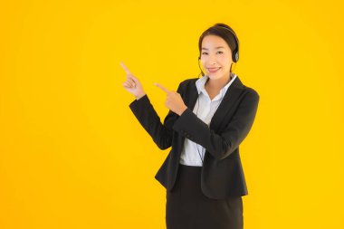 Portre güzel genç Asyalı kadın kulaklık ya da çağrı merkezi için kulaklık ya da tele pazarlama sarı izole arka planda.