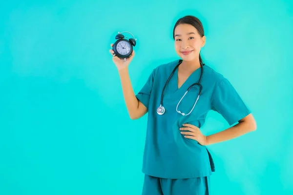 ポルトガルの美しい若いアジアの医師の女性ショークロックまたはアラーム上の青隔離された背景 — ストック写真