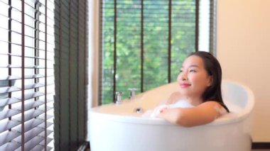 Güzel Asyalı bir kadının evde köpükle banyo yaptığı görüntüler.