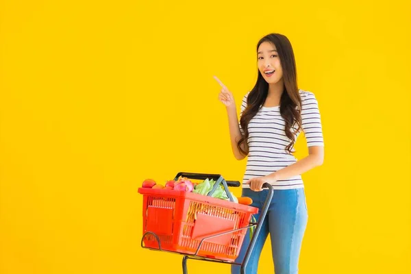 来自超级市场和黄色独立背景购物车的漂亮年轻亚洲女人的画像 — 图库照片
