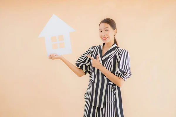 肖像画美しい若いアジアの女性は茶色の背景に家や家の紙のサインを表示 — ストック写真