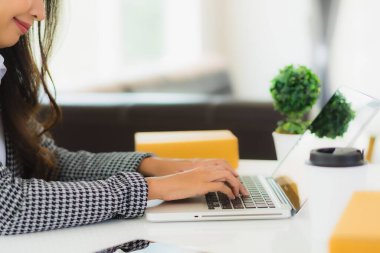 Güzel Asyalı iş kadını portresi evden bilgisayarlı cep telefonuyla karton kutuyla çevrimiçi alışveriş için hazır bekliyor.