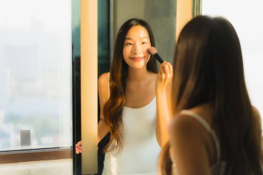 Güzel bir Asyalı kadın portresi makyaj malzemesi makyaj malzemesi ve yüz makyajı ile banyo içinde yüz maskesi.