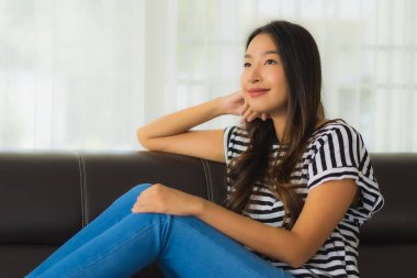 Güzel bir Asyalı kadın portresi. Mutlu bir gülümseme. Oturma odasındaki kanepede rahatla.