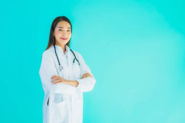 Klinikte ya da mavi izole edilmiş arka planda hastanede kullanmak üzere steteskoplu güzel Asyalı genç doktor kadın portresi.
