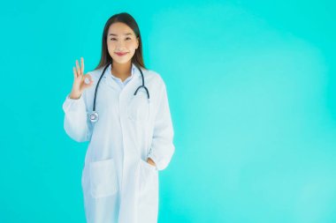 Klinikte ya da mavi izole edilmiş arka planda hastanede kullanmak üzere steteskoplu güzel Asyalı genç doktor kadın portresi.